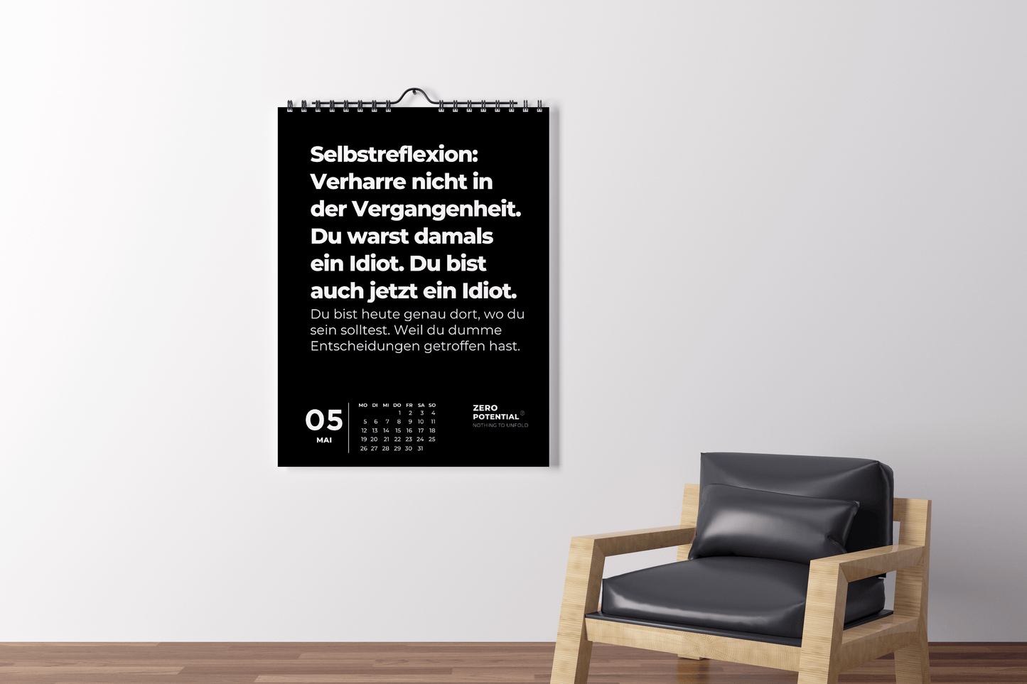 Ein Wandkalender aus dem Demotivierenden Wandkalender 2025 von ZERO POTENTIAL präsentiert den 5. Mai mit einem deutschen Zitat zur Selbstreflexion. Es wird an einer weißen Wand über einem modernen schwarzen Stuhl mit Holzrahmen angezeigt und bietet ungeschönte Wahrheiten, um zur Selbstreflexion anzuregen.